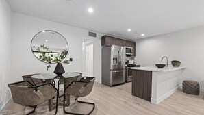 A modern kitchen with a central island, stainless steel appliances, and a dining area with a round table and chairs.