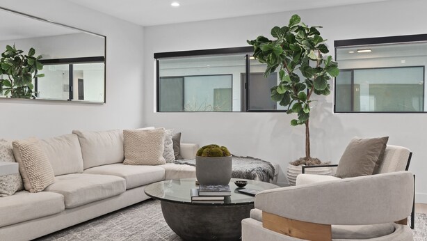 A modern living room with a sectional sofa, a round coffee table, and a potted plant.