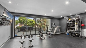 A modern gym with cardio equipment, weight machines, and a punching bag area.