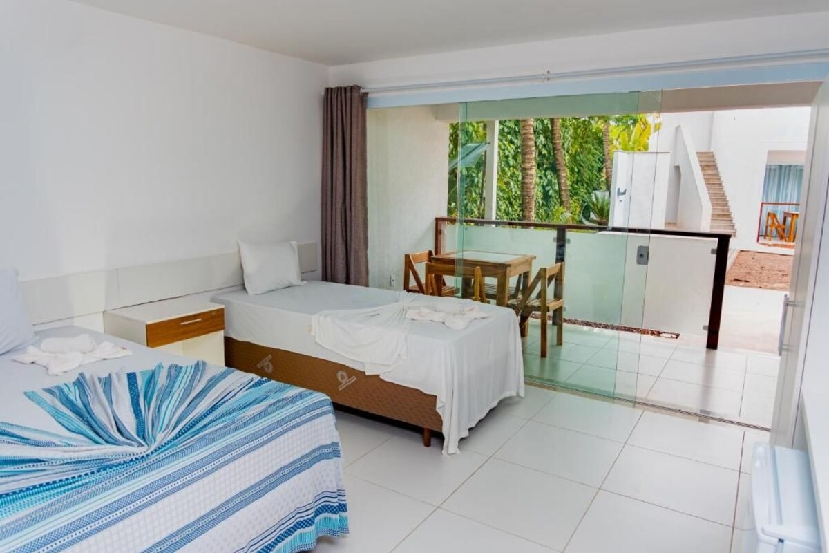 A bedroom with a bed, a bedside table, a chair, and a balcony with a glass door.