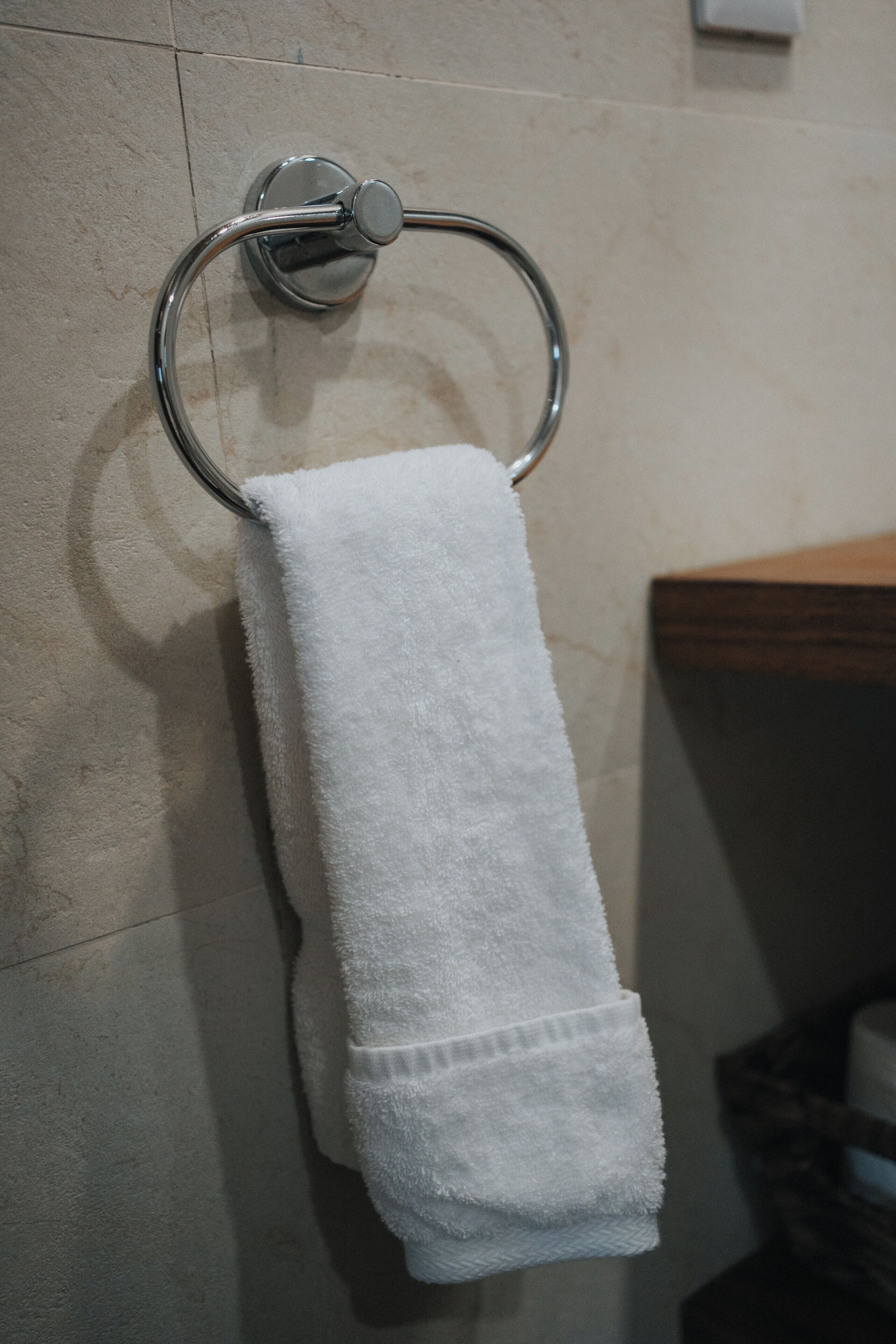 Une serviette blanche est suspendue à un porte-serviettes en métal, le tout adossé à un mur carrelé.