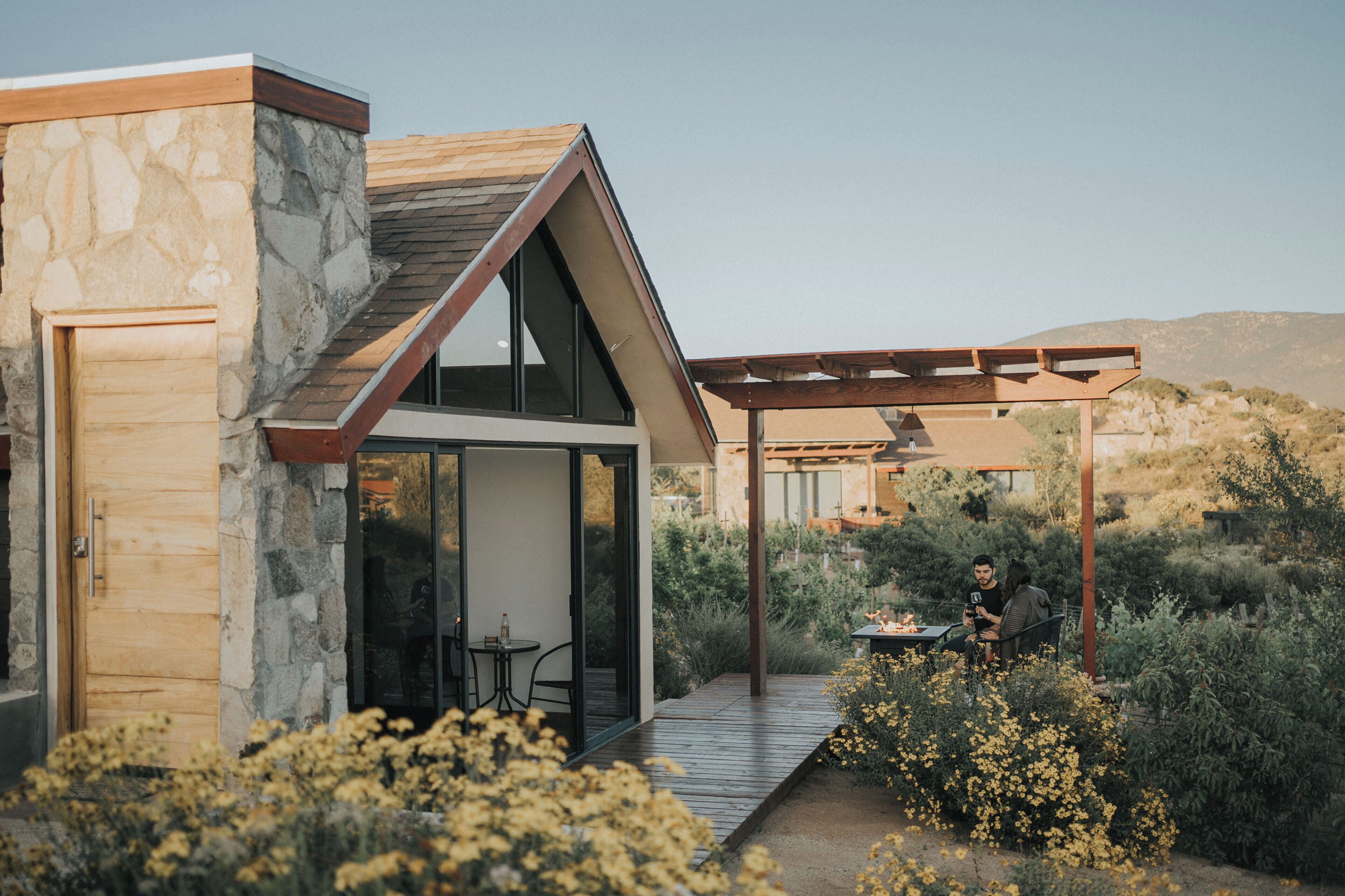 A modern house with a stone facade, large windows, and a wooden deck.