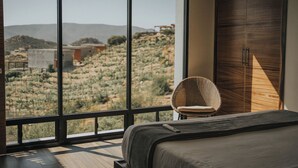 Un dormitorio con una ventana grande, una cama, una silla y un armario.