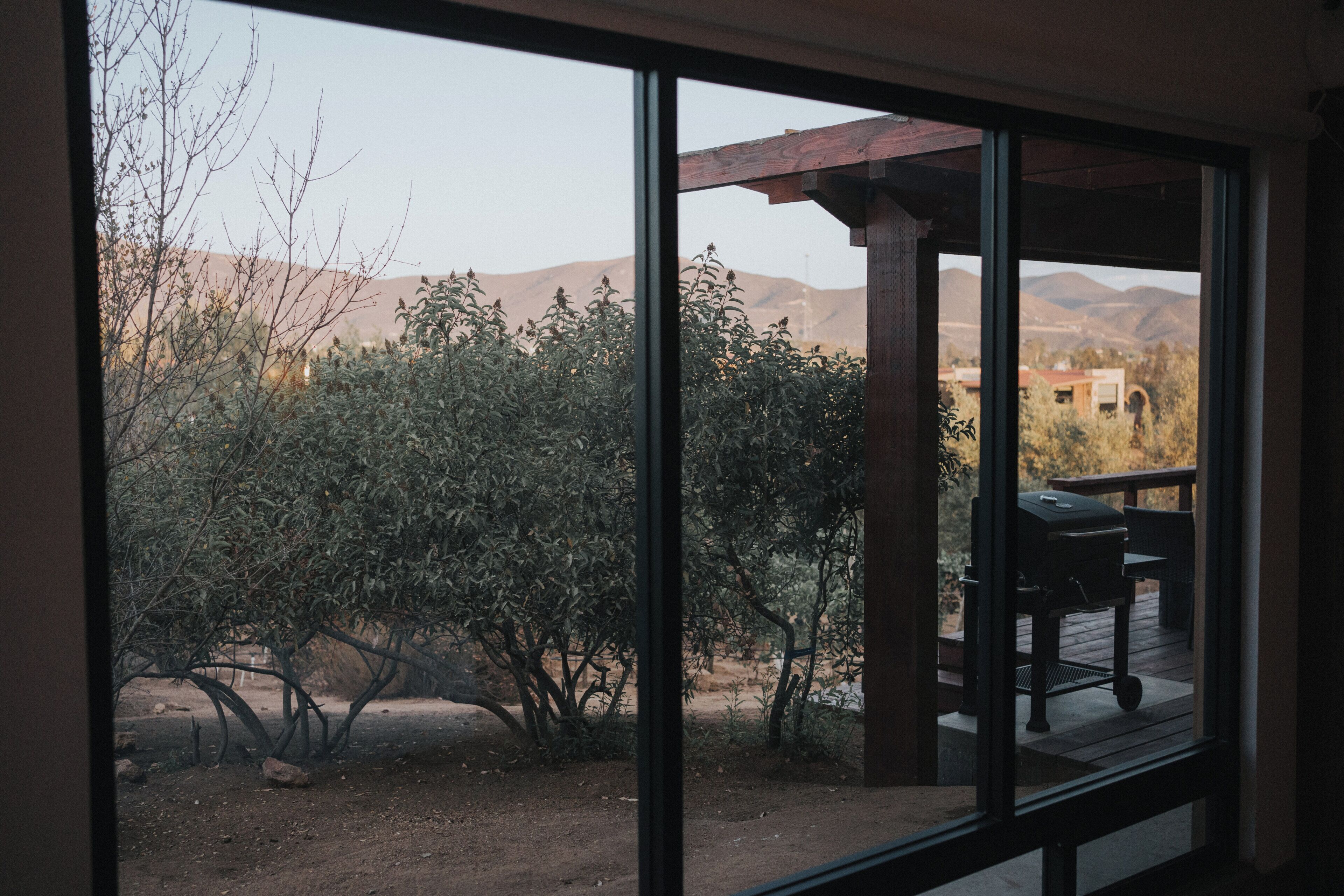 A view through a window of a patio area with a grill and outdoor furniture.