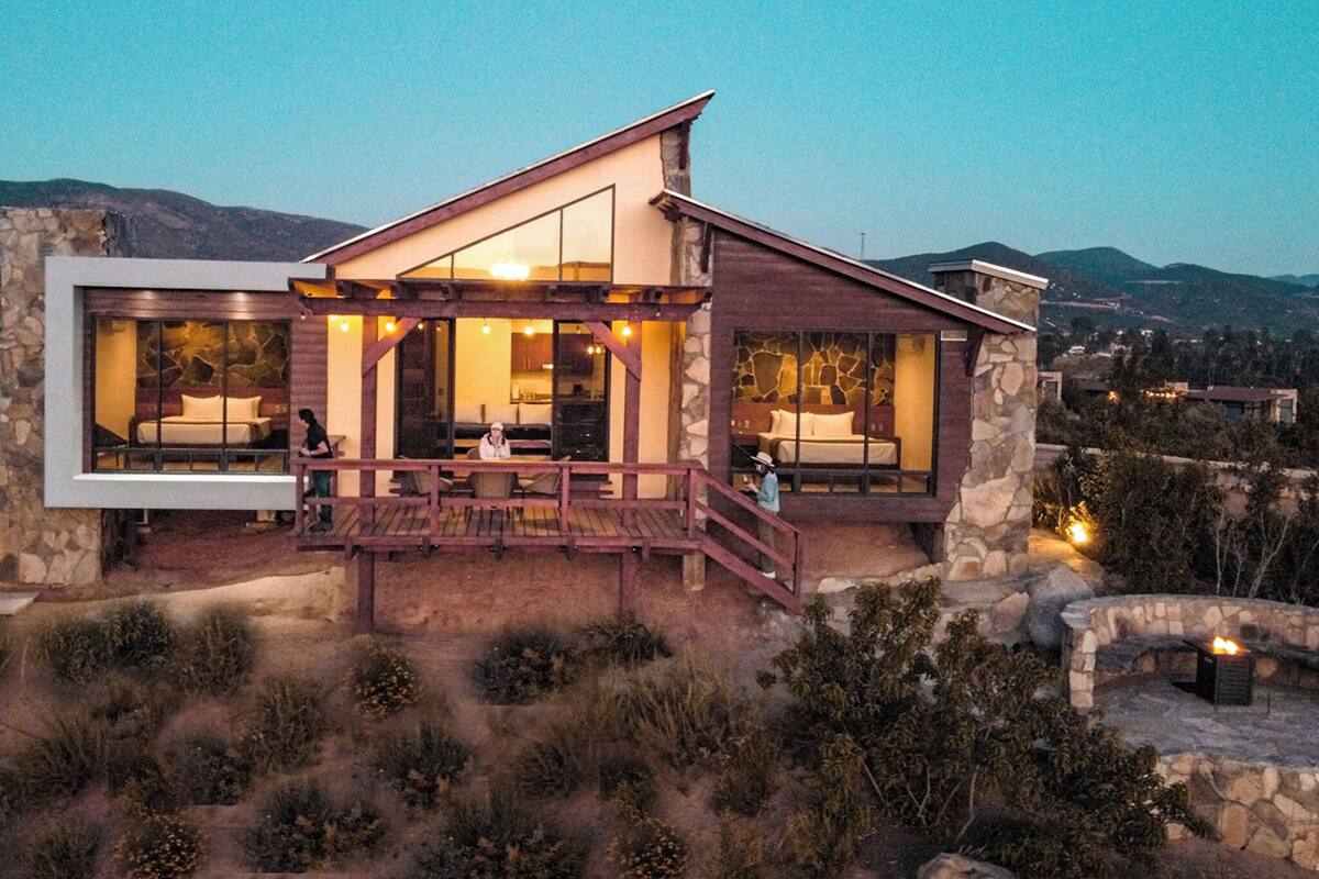Una casa moderna con amplios ventanales, fachada de piedra y terraza de madera.