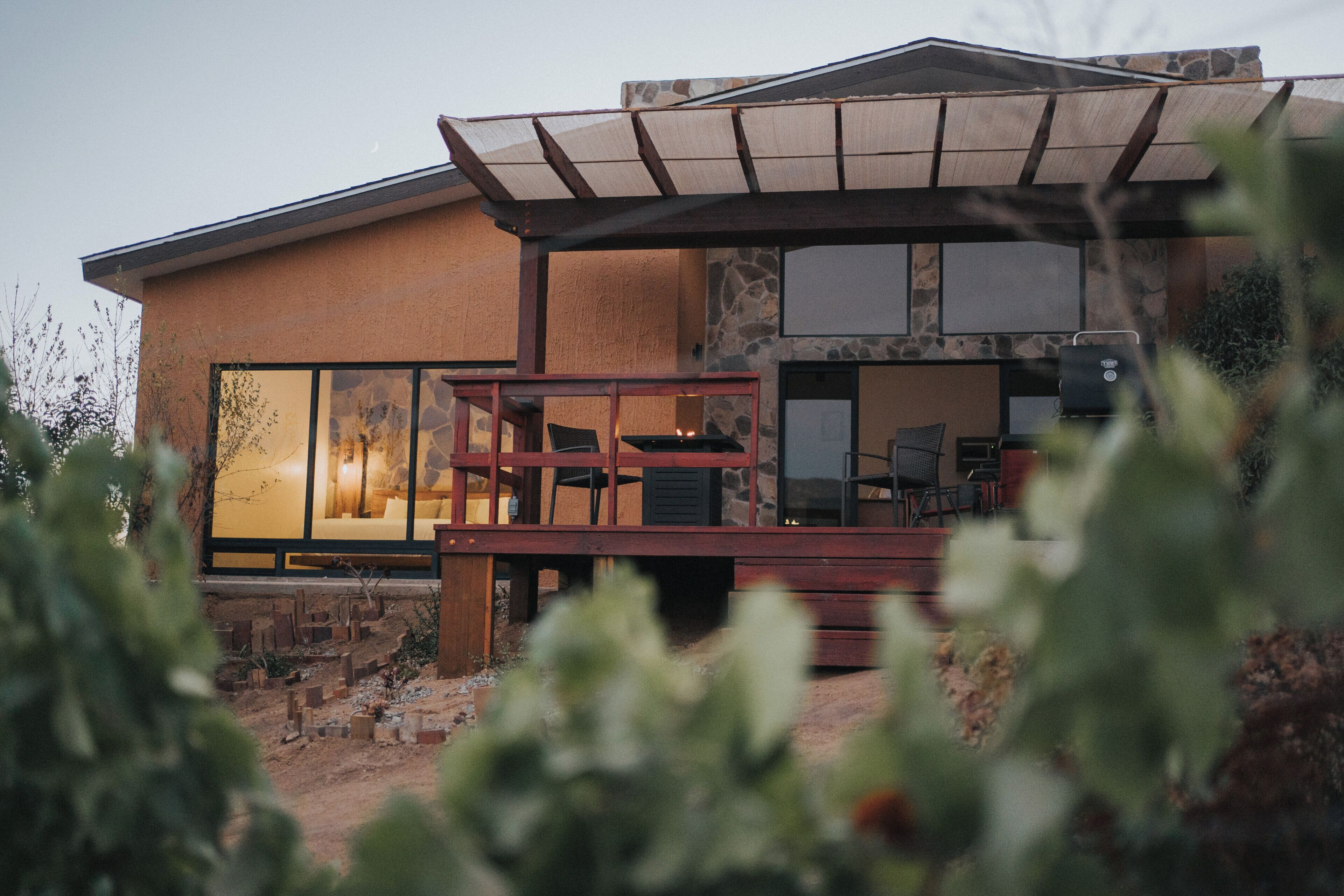 Une maison moderne dotée d’un patio, d’un barbecue et d’une grande fenêtre.