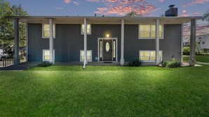 Una moderna casa a due piani con facciata simmetrica, ampie finestre e un prato curato.