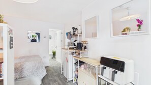 A compact, well-organized room with a bed, a kitchenette, a mirror, and a small dining area. - Portway Nook - 1 Bedroom Studio - Bishopston (Swansea)