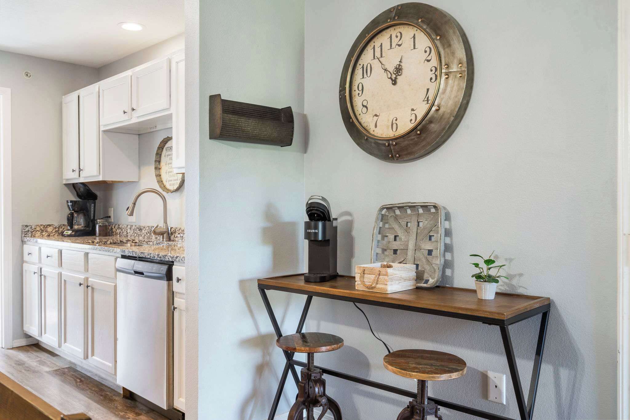 A kitchen with white cabinets, a coffee machine, and a clock on the wall.