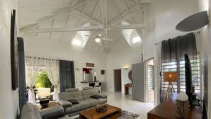 Uma sala de estar ampla com teto alto, um sofá, uma mesa de centro e um armário de madeira.