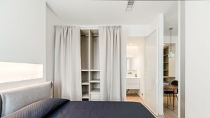 Un dormitorio con cama, armario y baño visible a través de una puerta abierta.