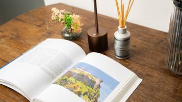 Un libro aperto con una fotografia sulla pagina destra, un vaso con canne palustri e una piccola pianta su un tavolo di legno.