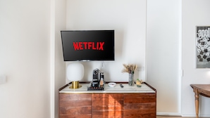 Una sala de estar moderna con un mueble de madera, una cafetera, un control remoto y un jarrón decorativo.