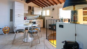 Une cuisine moderne avec des meubles blancs, une cuisinière à gaz et un coin repas comprenant une table ronde et des chaises rembourrées.