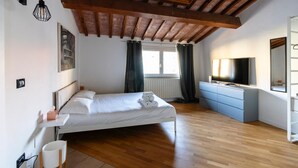 Une chambre moderne avec un plafond en bois, un lit, une télévision et une commode.