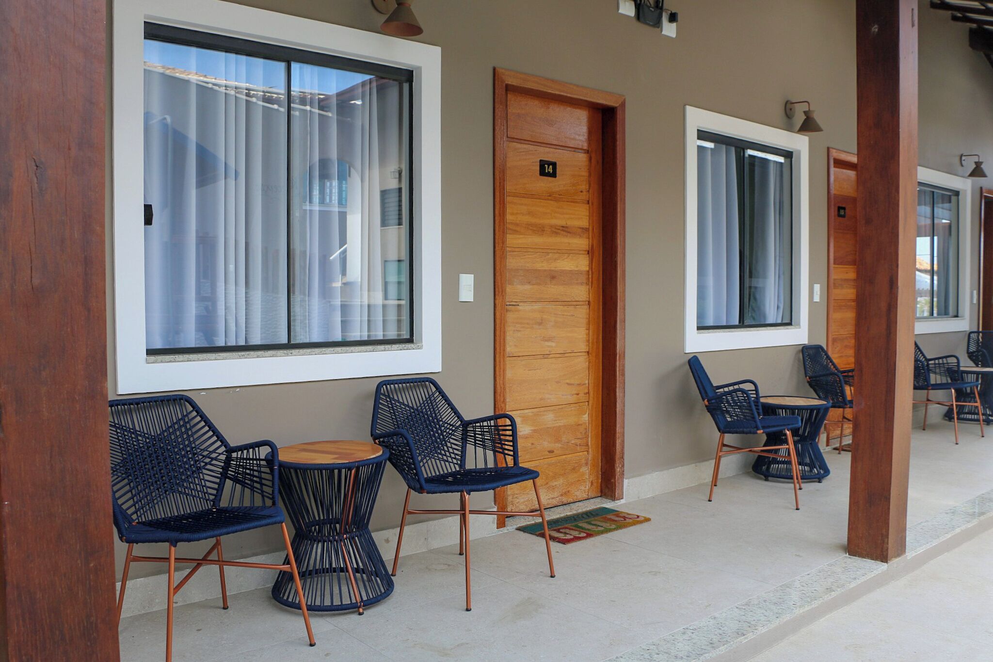 A covered outdoor seating area with wooden doors and large windows.