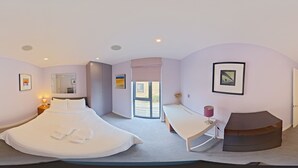 Une chambre moderne avec un grand lit, un bureau et une vue sur l’extérieur.