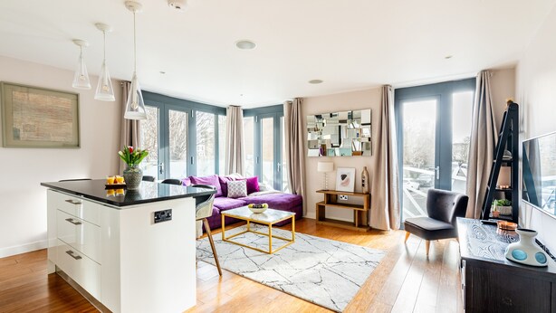 Un salon moderne avec un îlot de cuisine, un canapé, une table basse et un meuble pour la télévision.