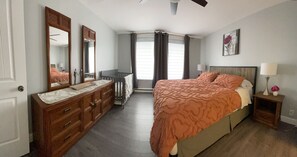 A bedroom with a large bed, a dresser, a mirror, a nightstand, and a window with curtains. - Full apartment, quick access with 40 Highway and 15 Highway. Free Parking (Montréal)