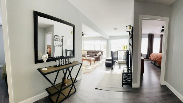 A spacious living area with a large mirror, a console table, and a staircase leading to another room.