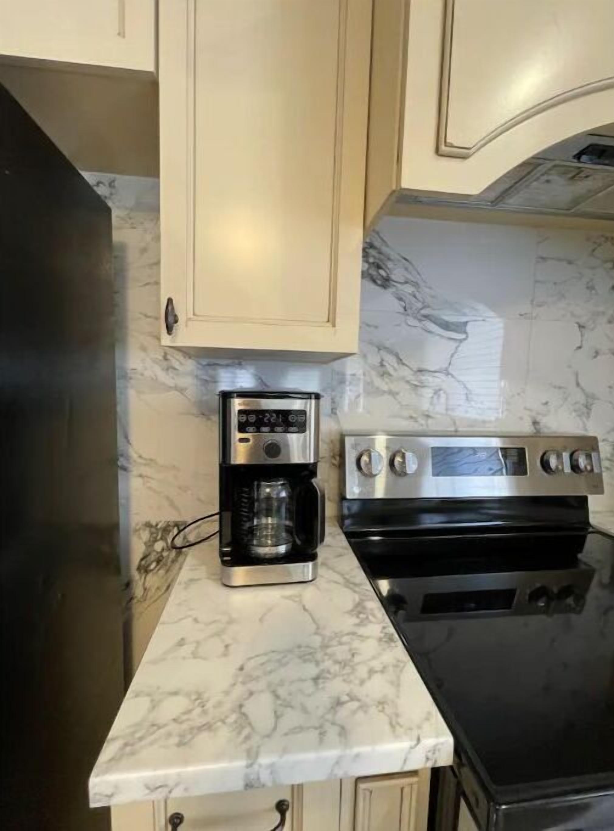 A kitchen with marble countertops, a coffee maker, and a stove.