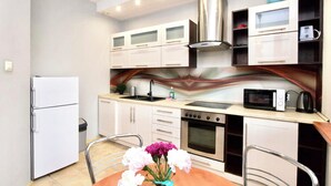 A compact kitchen with white cabinets, a stainless steel range hood, a microwave, and a sink.