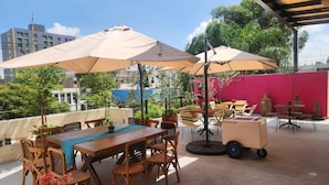 An outdoor patio with a wooden table and chairs, surrounded by umbrellas. - Hotel Consulado (Guadalajara)