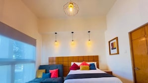 A bedroom with a bed, a sofa, a wooden headboard, and a window. - Hotel Consulado (Guadalajara)