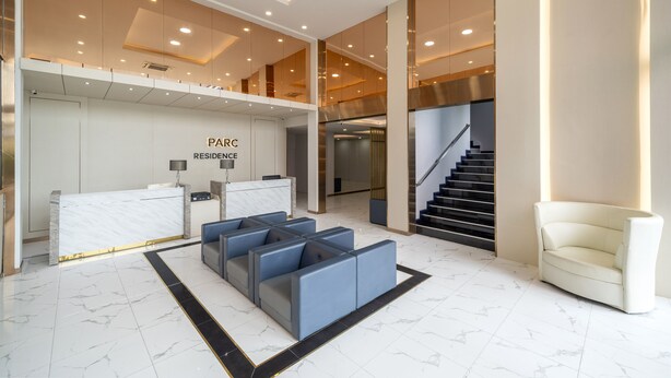 A modern reception area with a marble floor, a reception desk, and a staircase leading to an upper level. - The Parc Bangna (Bang Phli)