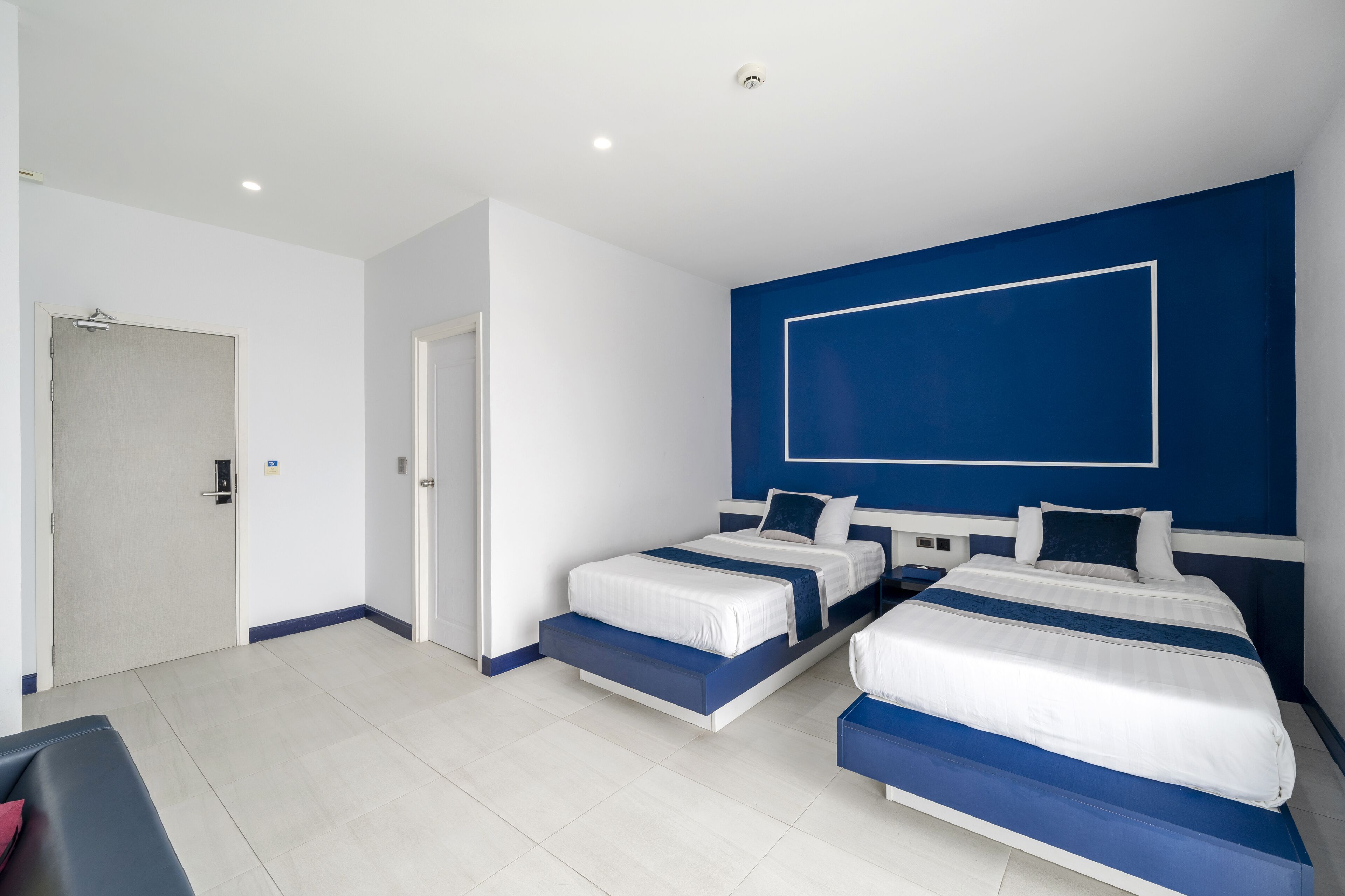 A modern hotel room with two beds, a large window, and a door.