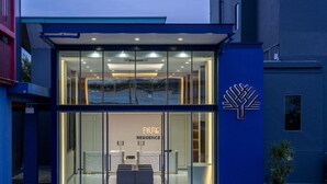 A modern building with a glass entrance, a reception desk, and a logo on the wall. - The Parc Bangna (Bang Phli)