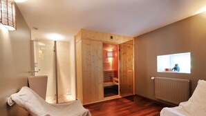 Ein Zimmer mit Holzboden, einer Glasdusche und einer Holzauna.
