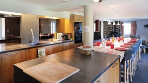 Eine moderne Küche mit einer großen Kochinsel, einem eingebauten Backofen und einem Essbereich mit roten Stühlen und einem Tisch für sechs Personen.