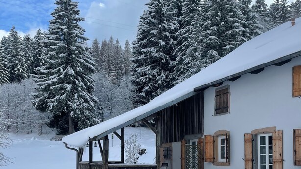 Ein mit Schnee bedecktes Gebäude mit einer Holzveranda und einem überdachten Bereich.