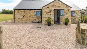 A stone building with a gravel driveway and two potted plants. - The Cottage (Chesterfield)