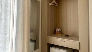 A hotel room with a built-in wardrobe, a small refrigerator, and an air conditioning unit. - Folklore B&B (Naples)