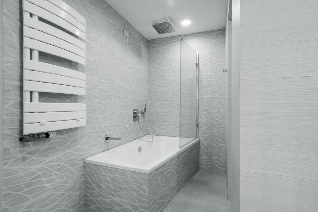 Une salle de bain moderne avec une baignoire sur pieds, une douche à parois de verre et un porte-serviettes fixé au mur.