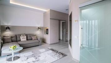 Una sala de estar moderna con un sofá, una mesita de centro y un ventanal de vidrio que da a un balcón.