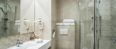 A modern bathroom with a glass-enclosed shower, a white sink, and a toilet.