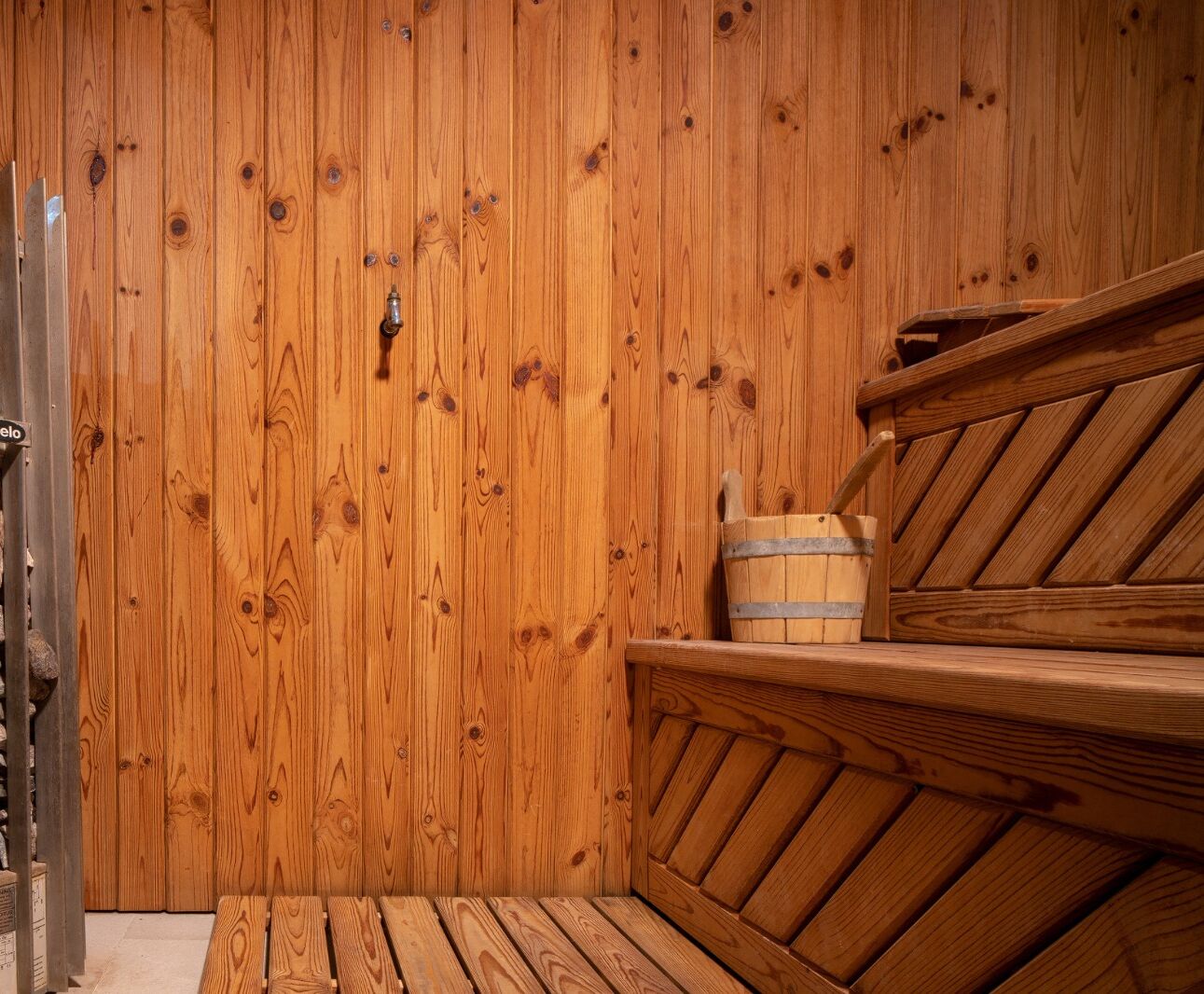 A wooden sauna with a bench and a bucket.