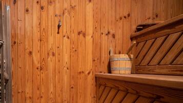 A wooden sauna with a bench and a bucket.