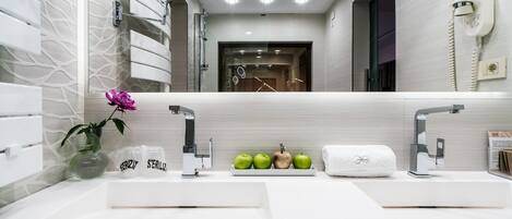 A modern bathroom with two sinks, a vanity mirror, and a towel rack.