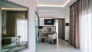 Una habitación de hotel moderna con separador de vidrio, televisor de pantalla plana, escritorio con silla y sofá.