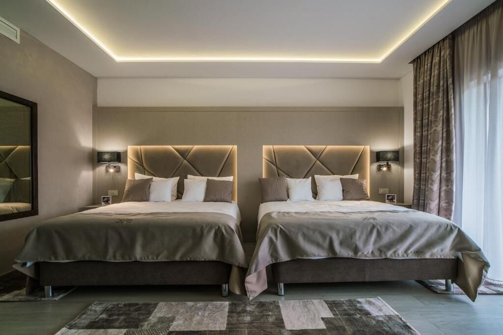 Une chambre d’hôtel moderne avec deux lits, un grand miroir et un luminaire au plafond.