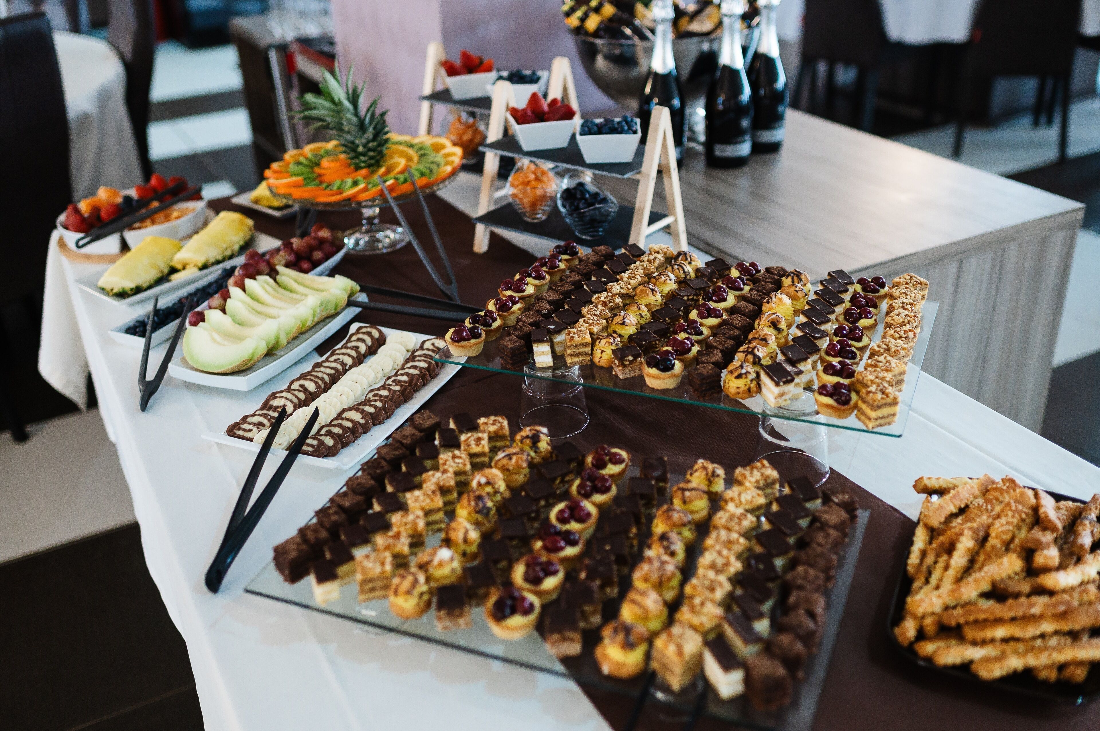 A buffet table with various desserts and fruits.