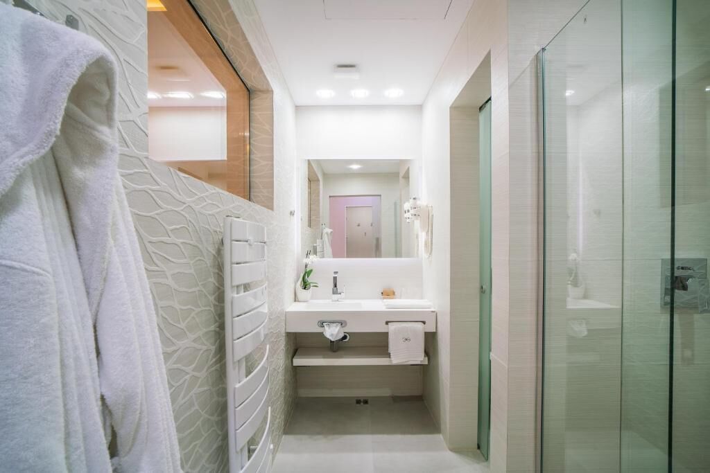 A modern bathroom with a glass shower enclosure, a white vanity with a mirror, and a towel rack.