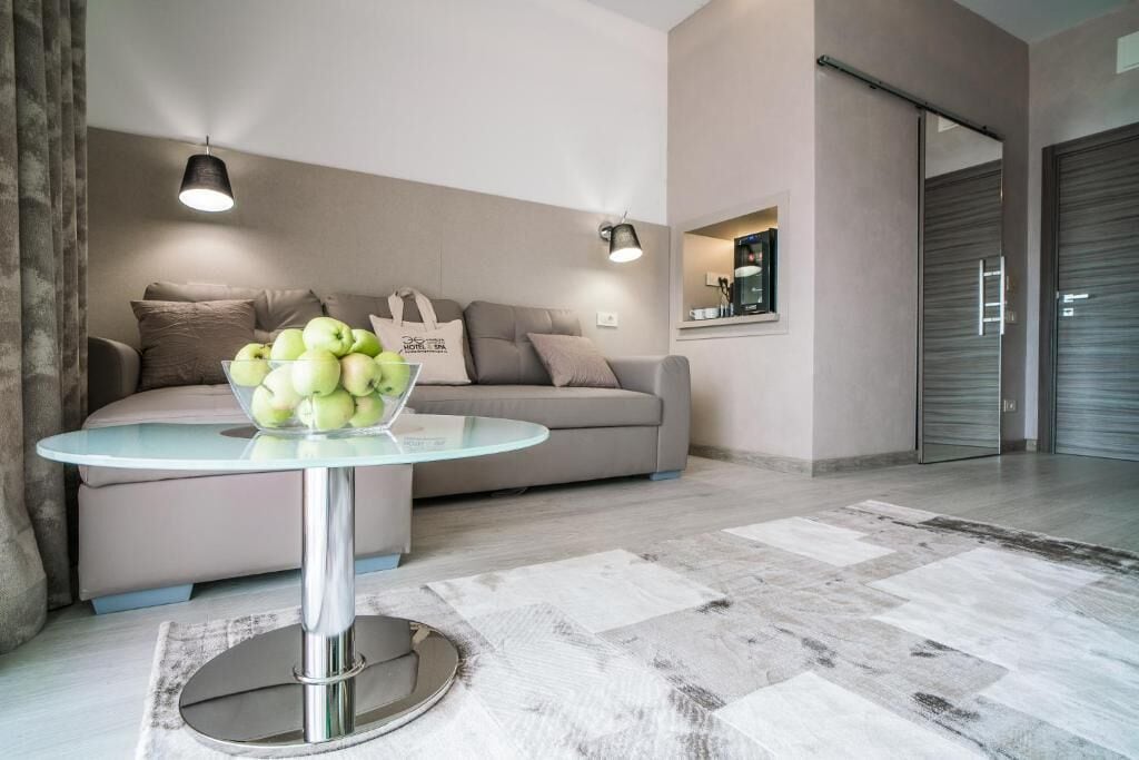 A modern living room with a glass-top coffee table, a beige sofa, and a bowl of green apples.