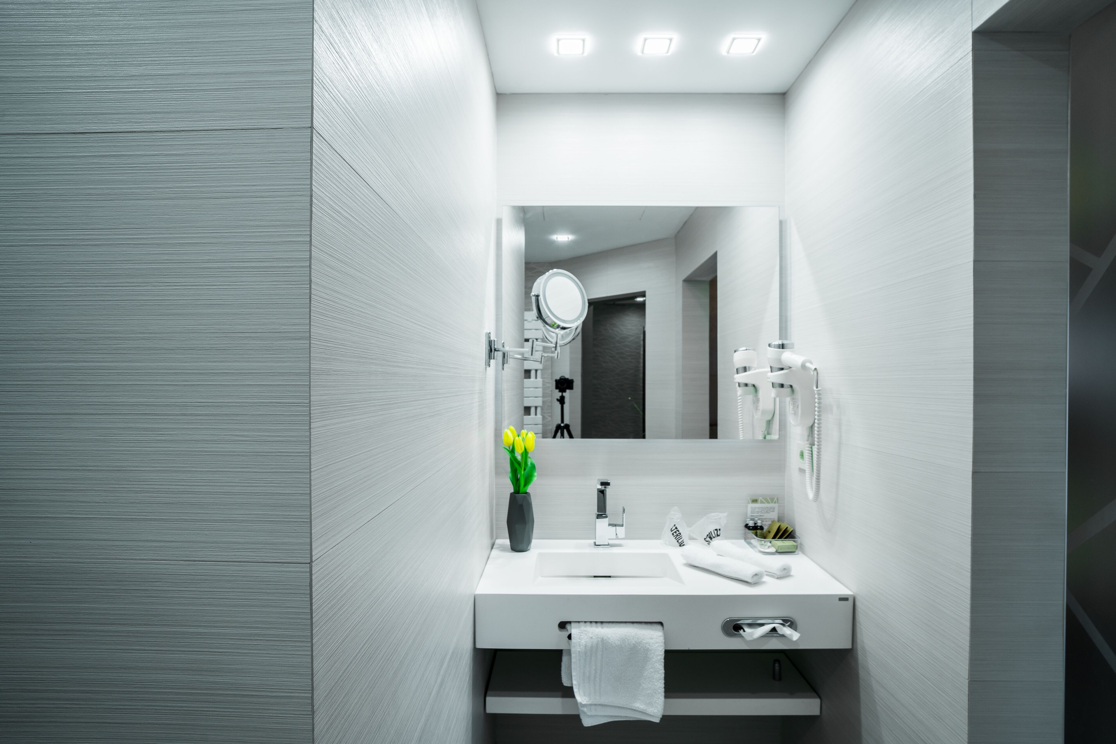 Un baño moderno con un tocador blanco, un espejo, un lavabo y un perchero para toallas.