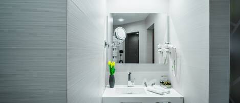 Un baño moderno con un tocador blanco, un espejo, un lavabo y un perchero para toallas.