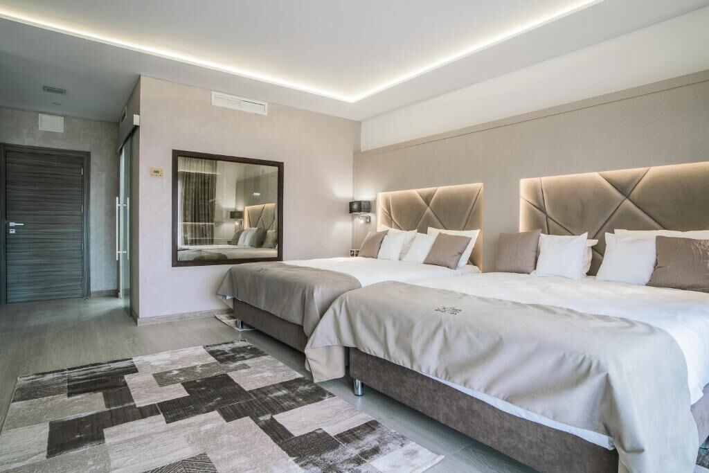 A modern hotel room with two beds, a large mirror, and a geometric rug.